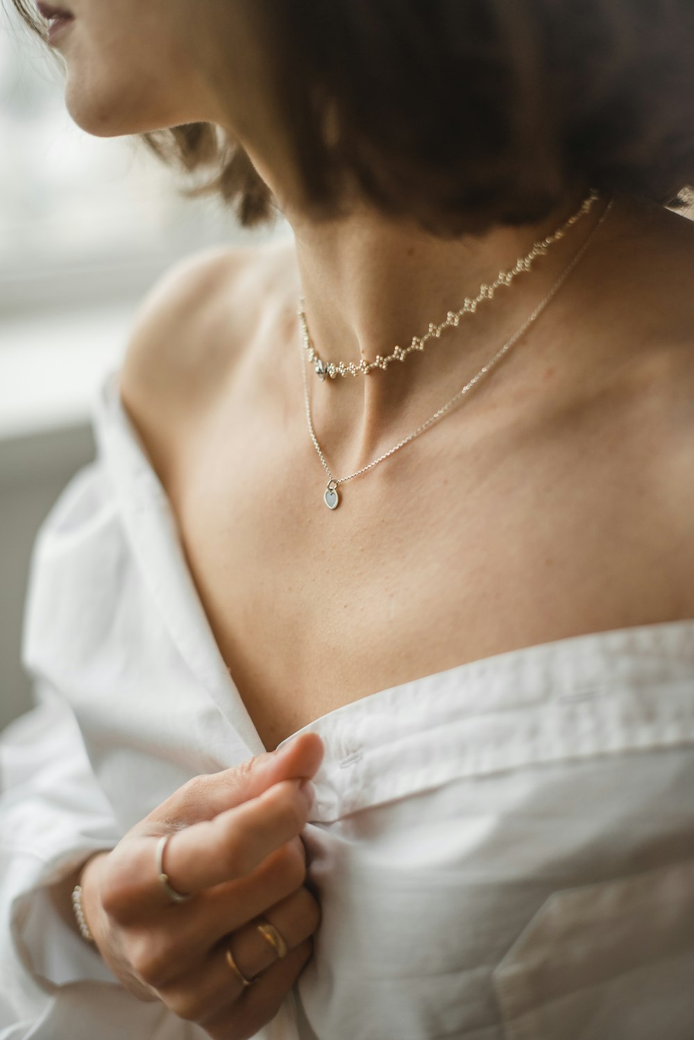 Collares finos superpuestos sobre camisa blanca