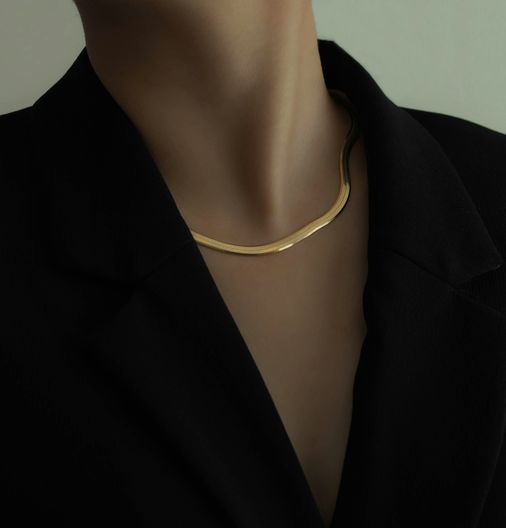 Collar de oro tipo espiga sobre blazer negro